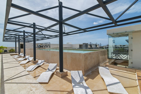 This stunning rooftop features a sleek infinity pool with crystal-clear water, surrounded by modern lounge chairs under a stylish pergola. Perfect for guests seeking a luxurious, sun-soaked retreat with panoramic views!