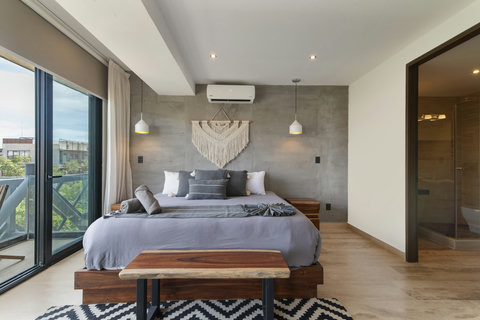 Enjoy a stylish bedroom with a cozy bed, modern decor, and natural wood accents. Relax with plush pillows and a chic rug—perfect for guests seeking comfort!