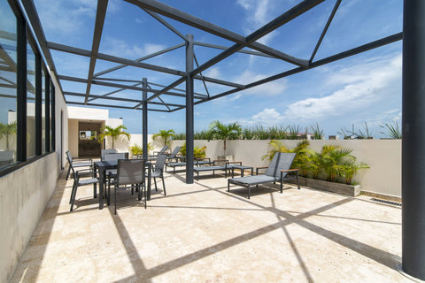 Discover the charm of Palais Tulum’s terrace, complete with cozy chairs and sunlit tables—perfect for unwinding and enjoying peaceful moments.