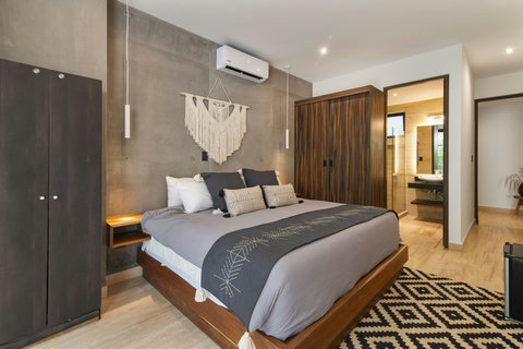 Modern second bedroom with boho decor, king-size bed, wood closets, and ensuite bathroom. Perfect for a stylish and cozy stay in Tulum.