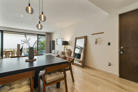 Chic dining area with black table, wood chairs & pendant lights. Large windows open to a private pool and garden, offering a cozy, elegant setting.