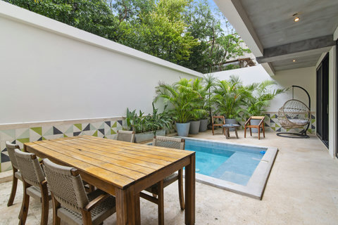 Unwind in this Tulum patio with a private pool, grill, and cozy dining area surrounded by lush greenery.