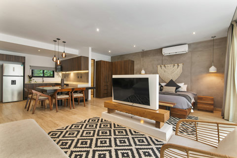 Modern apartment with sleek kitchen, cozy bedroom & chic dining area. Enjoy wood accents, pendant lights, and a TV with natural light flooding in.