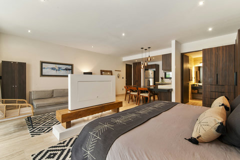 Stylish apartment with cozy bedroom, sleek sofa & chic dining area. Features modern bed, wood furniture & pendant lights for a comfy, elegant stay.