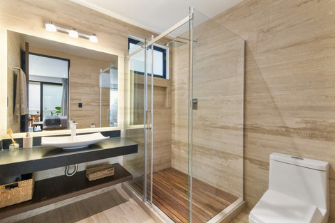 Luxurious bathroom with glass shower, black vanity & stone tiles. Bright, spacious, and perfect for unwinding in comfort and style.