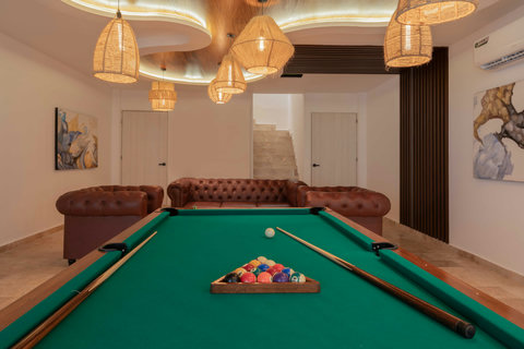 Elegant lounge with a timeless pool table, cozy leather sofas, and artistic wall pieces. The warm lighting and sleek design create a refined yet relaxed atmosphere ideal for entertainment and comfort.