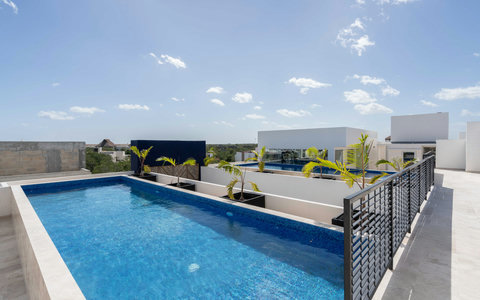 Unwind in the tranquil shared rooftop pool, where modern design meets lush surroundings. Perfect for watching sunsets, feeling the gentle breeze, and enjoying a relaxing vacation atmosphere.