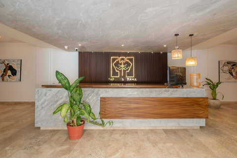Elegant reception area featuring a marble front desk, warm wooden details, and soft ambient lighting. The cozy lounge and lush plants create a welcoming atmosphere for guests.