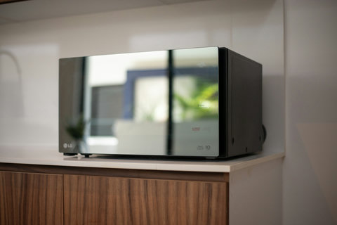 Sleek and functional, this modern kitchen showcases an LG microwave, ideal for stylish cooking spaces with wooden cabinets and a contemporary touch.