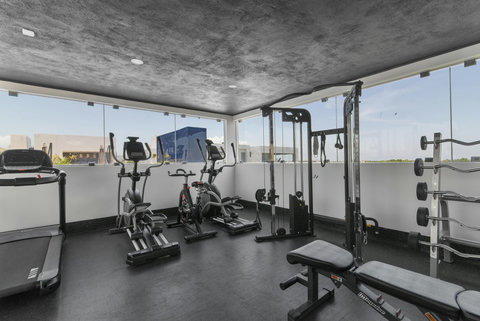 Modern rooftop gym featuring cardio machines, a full strength station, and a complete dumbbell set. Stay active while enjoying panoramic views and fresh air in this bright, motivating fitness space.