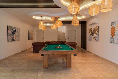 Stylish lounge area featuring a classic pool table, elegant leather sofas, and artistic decor. Warm lighting and modern design create the perfect space to relax or enjoy a friendly game.