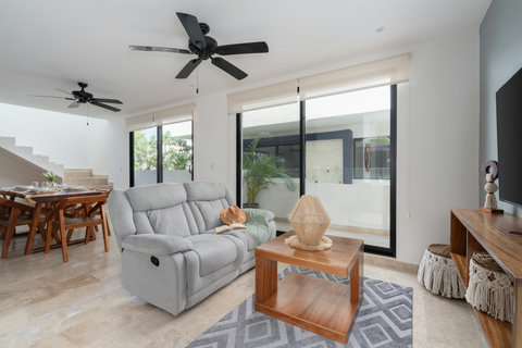 Elegant living space blending comfort and style, featuring a plush gray recliner, wooden coffee table, and warm tones that invite you to unwind and enjoy serene tropical living.