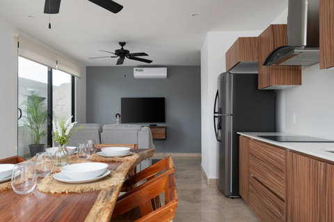 Stylish open-plan living with a modern kitchen, sleek wooden finishes, and a cozy lounge. Enjoy meals at the rustic dining table or relax on the sofa while watching TV in this bright, airy space.