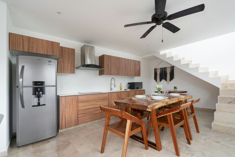 Sleek open-concept kitchen with wood finishes, stainless steel appliances, and a solid wood dining table—perfect for stylish stays in Tulum.