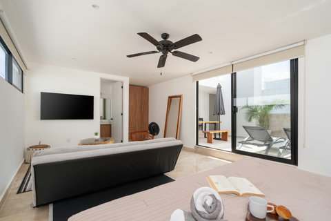 Third bedroom with king size bed, sofa bed, A/C, TV, en-suite bathroom, and access to a private patio with lounge chair—ideal for comfort and relaxation.