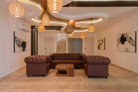 Elegant waiting lounge featuring rich leather Chesterfield sofas, warm ambient lighting, and modern abstract art. The refined design and cozy atmosphere make it an inviting space to relax and unwind.