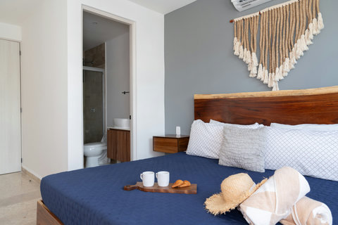 Bright master bedroom featuring a king-size bed, private en-suite bathroom, A/C, and natural wood details. A perfect retreat for restful nights and serene mornings in a stylish and cozy atmosphere.