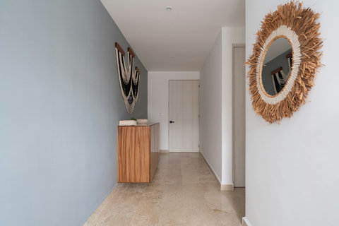 Bright hallway with elegant neutral tones, decorative mirror, and stylish wall art. The wooden console adds warmth, creating a welcoming entryway that sets the tone for the home’s modern design.