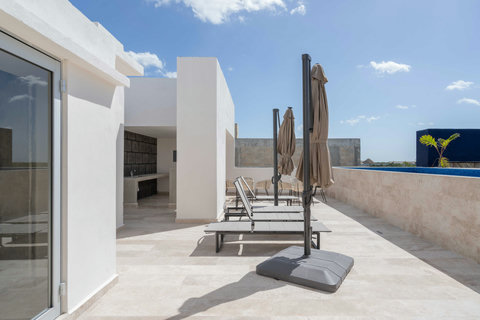 Modern shared rooftop featuring sun loungers, umbrellas, and a poolside seating area. Perfect for relaxing, sunbathing, or enjoying a peaceful afternoon under the open sky.