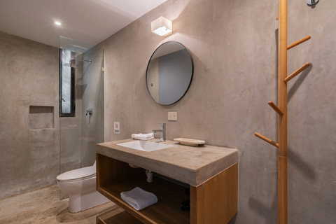 Modern bathroom with a sleek concrete finish, glass shower, warm lighting, and minimalist details designed for a calm, spa-like experience.