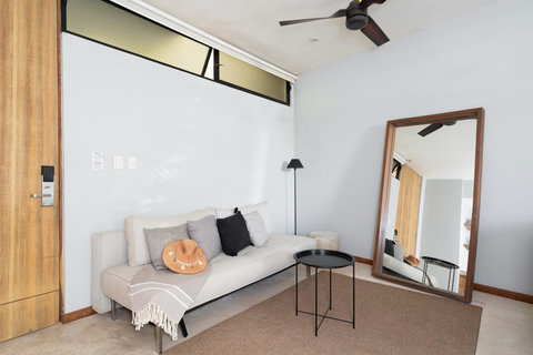 Cozy living corner with a soft neutral sofa, warm textures, and a large floor mirror that opens up the space—perfect for relaxing after a day in Tulum.