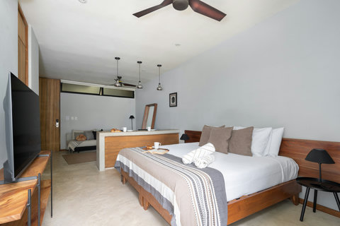 A bright studio featuring a cozy bed, warm wooden accents, and a sleek 50-inch TV—designed for a modern, comfortable stay with everything you need close at hand.