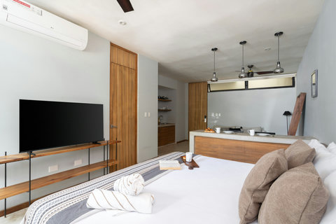 Bright studio layout with a comfy bed, wooden finishes, and a sleek TV setup—offering a cozy, modern stay with everything within reach.