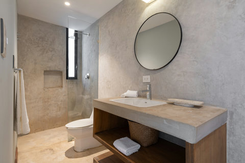 A cozy bathroom featuring a modern sink, a spacious mirror, and a refreshing rain shower. This inviting space is designed to make your daily routine feel relaxing, comfortable, and effortlessly stylish.