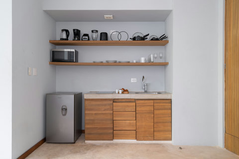A cozy, compact kitchen with everything you need: fridge, stove, pots, pans, and a coffee maker. Perfect for preparing meals comfortably during your stay in a practical and inviting space.