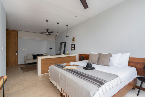 Enjoy a bright, modern studio featuring a plush king-size bed, warm wooden accents, a cozy dining area, a comfortable sofa, and a large mirror. This stylish space is designed to provide comfort, convenience, and a relaxing stay.