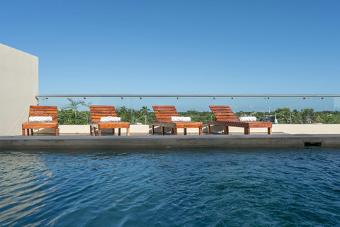 Unwind at a serene rooftop pool featuring comfy loungers and open-air views. Ideal for sunbathing, swimming, or simply enjoying a peaceful outdoor retreat.