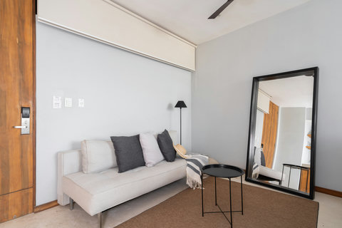 Cozy living area with an elegant sofa, large mirror, and inviting charm.