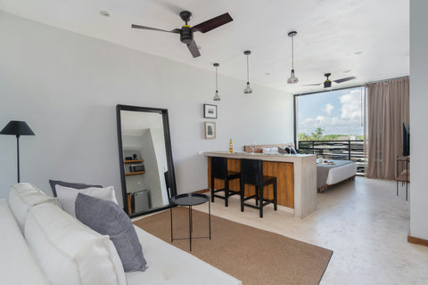 Relax in this modern open-plan living space with a cozy dining bar and calming views of lush greenery—ideal for working, unwinding, or enjoying peaceful moments.