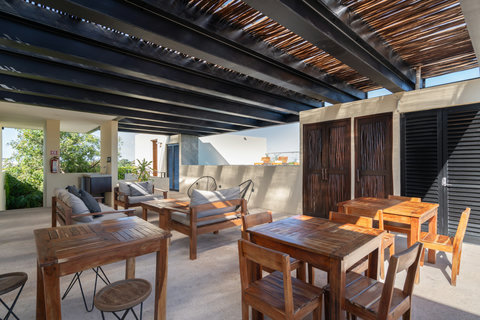 Relax in this cozy lounge featuring warm wooden tables, comfortable chairs, and open space—ideal for reading, working, or enjoying a calm, inviting atmosphere.