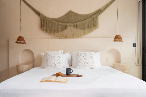 A spacious king-size bed dressed in soft linens and natural textures, designed for deep rest and ultimate comfort. The perfect centerpiece for slow mornings and restorative nights.