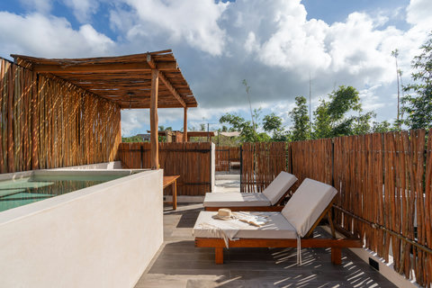 Unwind at the rooftop retreat featuring a refreshing plunge pool, comfy lounge chairs, and a rustic bamboo fence, offering a serene tropical escape with sun-soaked relaxation.