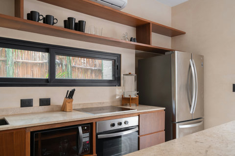 Designed with simplicity and warmth, this kitchen includes open wooden shelves, modern appliances, and a clean layout that invites relaxed cooking, morning coffee rituals, and effortless everyday meals.