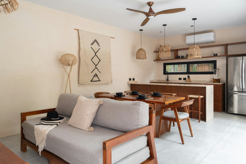 A warm, open-concept living space featuring natural textures, wooden details, and soft neutral tones. The cozy sofa, dining area, and modern kitchen create a relaxed, stylish setting perfect for everyday living.