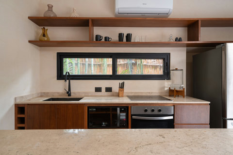 A fully equipped modern kitchen featuring warm wood finishes, open shelving, and quality appliances. Designed for comfort and functionality, it’s perfect for preparing meals while enjoying a bright, natural atmosphere.