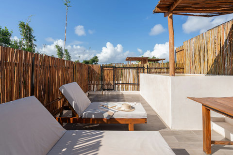Relax on a peaceful rooftop oasis featuring a plunge pool, cozy loungers, a wooden table, and bamboo fencing. A tropical retreat designed for sun-soaked days and tranquil moments.