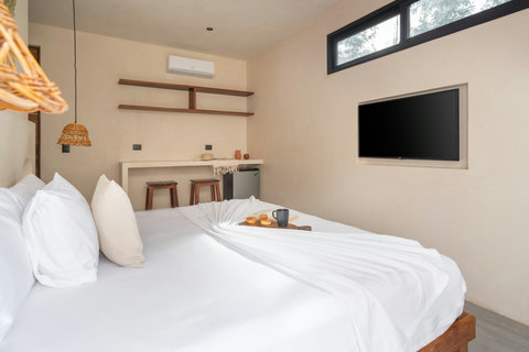 Cozy bedroom with a king-size bed, wall-mounted TV, rustic pendant lighting, and minimalist decor. Open shelving and a built-in bar add both style and functionality.