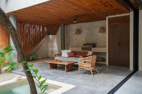 Relax in a cozy outdoor retreat with a bamboo-accented ceiling, sofa, rattan pendant lights, and inviting lounge area. Natural textures create a serene and peaceful escape.