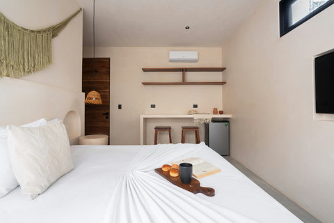 Cozy bedroom featuring a king-size bed, sleek wall-mounted TV, rustic woven pendant lighting, and minimalist décor. Open shelving and a stylish bar area add both functionality and a refined touch.