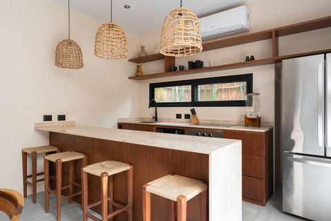 Stylish kitchen bar designed with natural stone surfaces, warm wood accents, and handcrafted stools. An inviting space for breakfast, casual meals, or socializing in a cozy yet refined ambiance.