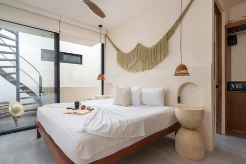 Elegant bedroom with a cozy boho design, king-size bed, wall-mounted TV, and warm rattan lighting. A balcony features a spiral staircase leading up to a private rooftop terrace with a second pool.
