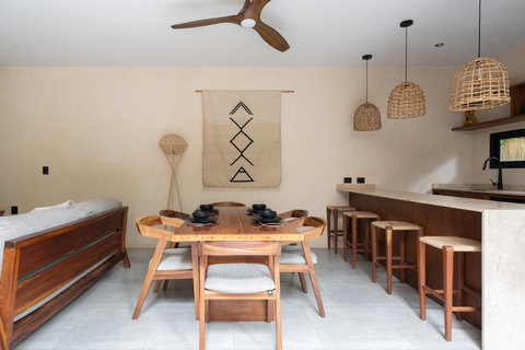 An inviting open-plan kitchen and dining space with artisan wood furnishings and soft natural tones, creating a refined yet relaxed atmosphere ideal for comfort and connection.