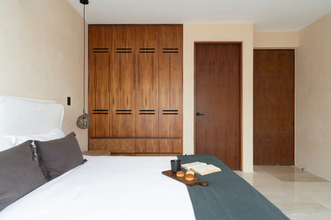 Spacious bedroom with a comfortable bed, elegant decor, and a large built-in wooden closet. A serene and functional space designed for rest and convenience.