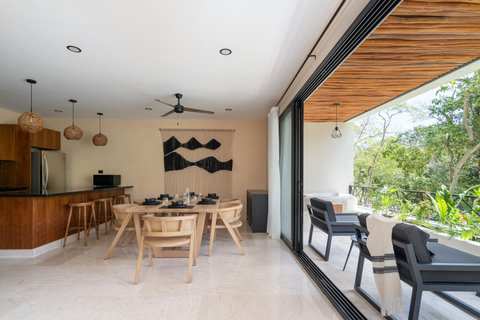 Spacious dining area with modern design and warm wood finishes, seamlessly connected to a private terrace with a jacuzzi and lush nature views. Bright, inviting, and perfect for memorable gatherings.