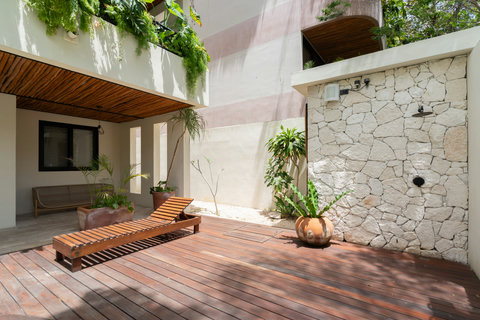 Relaxing outdoor terrace with wooden deck, lounge chair, and lush tropical plants. A peaceful space to unwind, soak up the sun, or enjoy quiet moments surrounded by nature.
