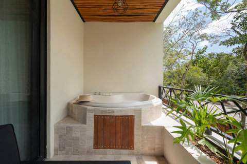 Private terrace with a relaxing jacuzzi, surrounded by tropical greenery and warm natural finishes. A peaceful retreat to unwind while enjoying serene jungle views.
